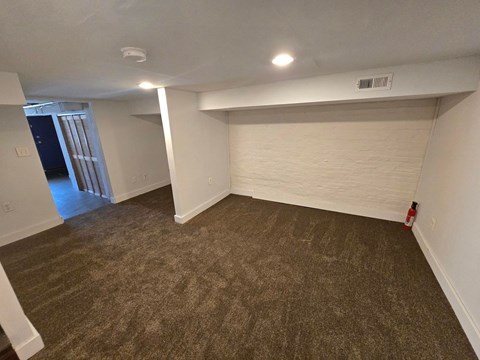 A room with a carpeted floor and a fireplace on the wall.