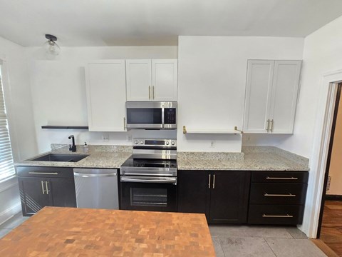 A kitchen with black cabinets and a wooden table.