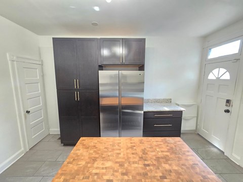 A kitchen with a wooden table and a black fridge.