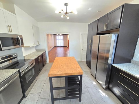 A kitchen with a wooden table and stainless steel appliances.