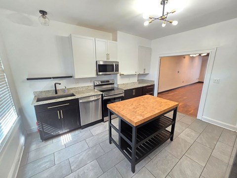 A kitchen with black cabinets and a wooden island.