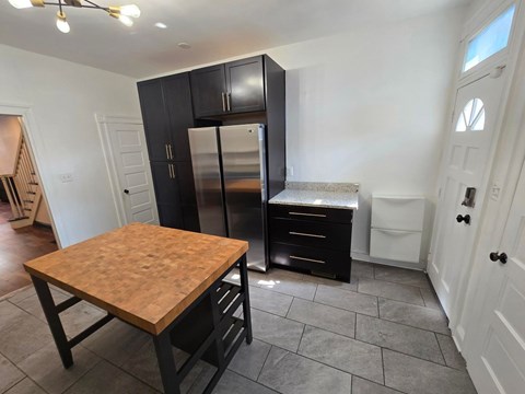A kitchen with a wooden table and black cabinets.