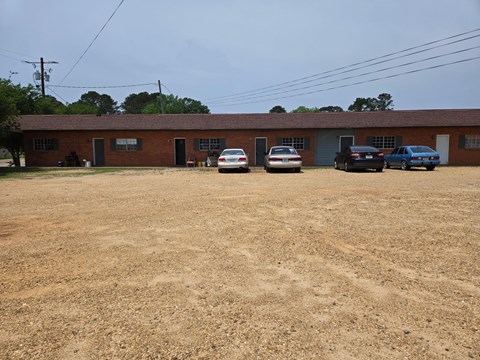 A parking lot with a building and cars parked in front.