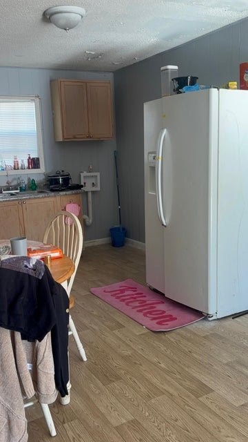 A kitchen with a white refrigerator and wooden floors.