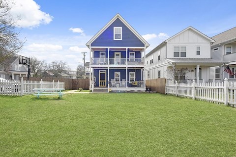 A blue house with a white picket fence in front.