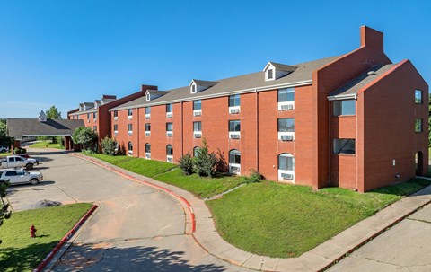 A red brick building with a green lawn in front.