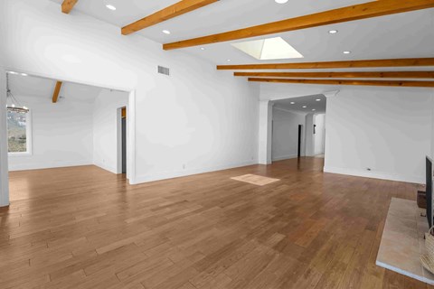 A spacious room with wooden floors and white walls.