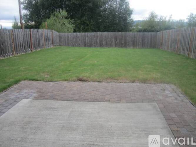A backyard with a wooden fence and a brick patio.