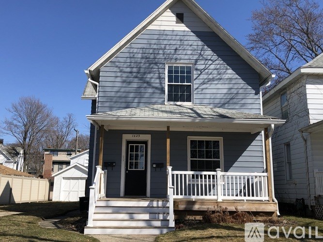 A blue house with a white porch and a black door.