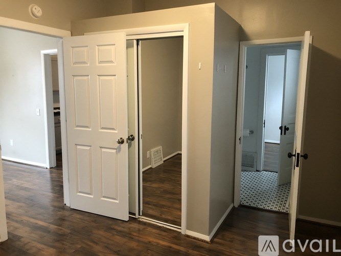 A room with a white door and a mirror on the wall.