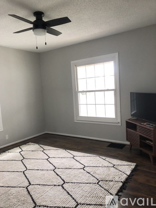 A room with a ceiling fan, a window, and a rug on the floor.