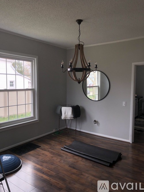 A room with a wooden floor, a chandelier, and a mirror.