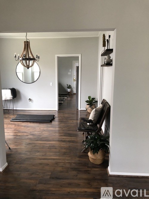 A living room with a black chair and a round mirror on the wall.