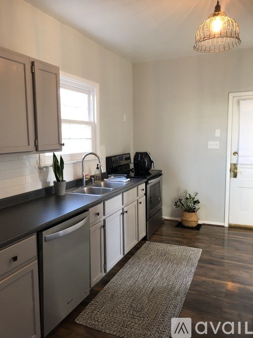 A kitchen with a sink, dishwasher, and a window.
