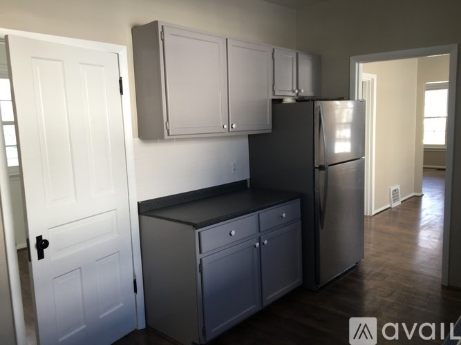 A kitchen with a refrigerator, cabinets, and a door.