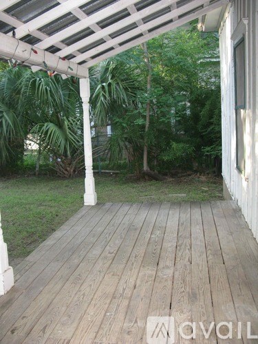 A wooden deck with a white pergola and trees in the background.
