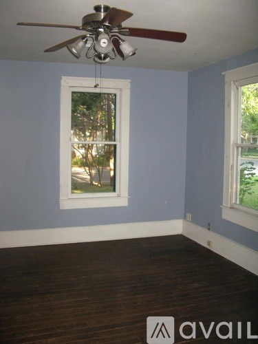 A room with a ceiling fan and two windows.