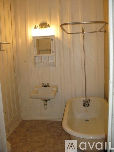 A small white sink is mounted on a wall next to a bathtub.