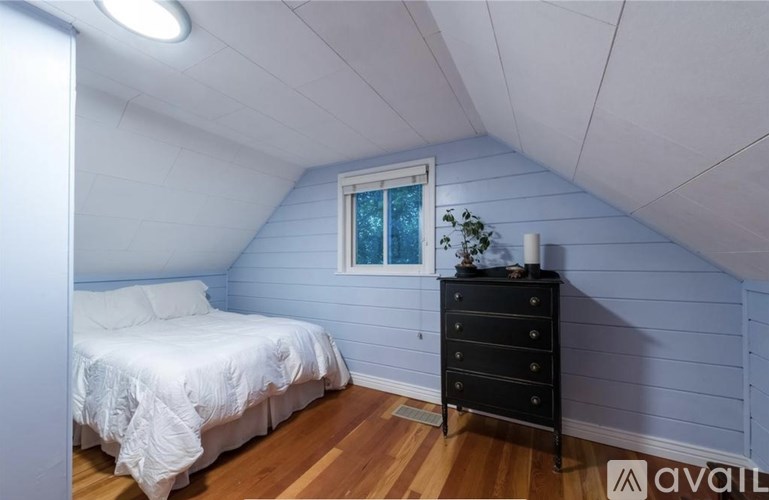 A bedroom with a bed, dresser, and window.