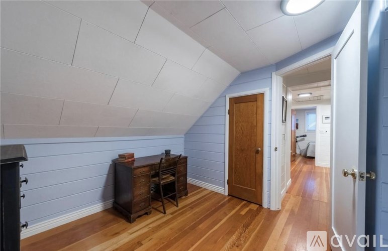 A room with a wooden floor and a white ceiling with a door on the right.