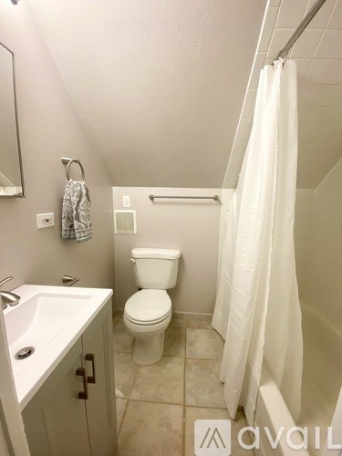 A white bathroom with a toilet, sink, and shower.