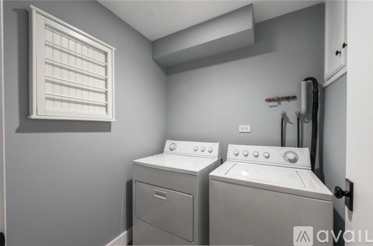 A laundry room with two washing machines and a window.