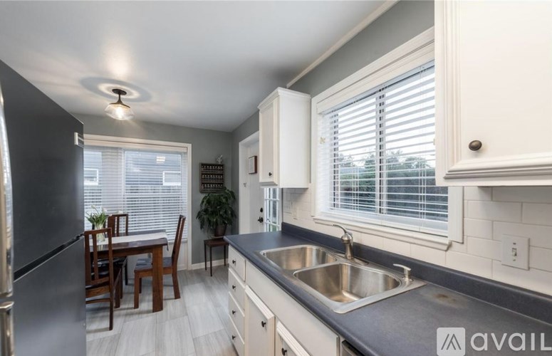 A kitchen with a refrigerator, sink, and dining table.
