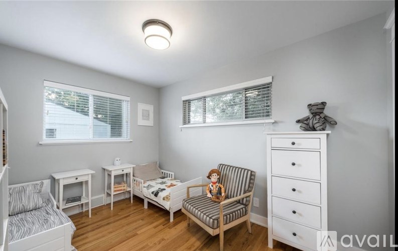 A doll is sitting on a striped chair in a room with white furniture.