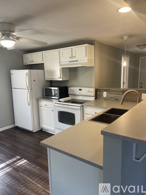 A kitchen with white appliances and a wooden floor.