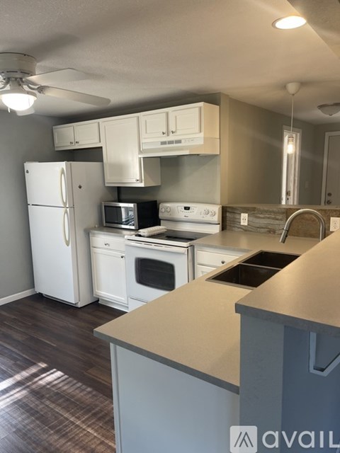 A kitchen with white appliances and a wooden floor.