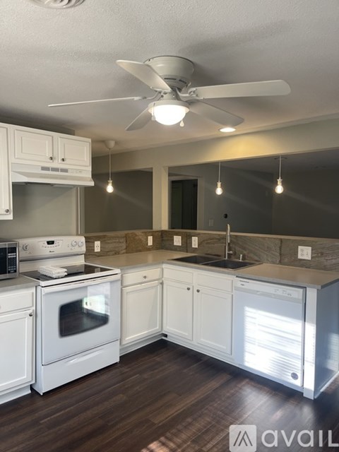 A kitchen with white appliances and cabinets.