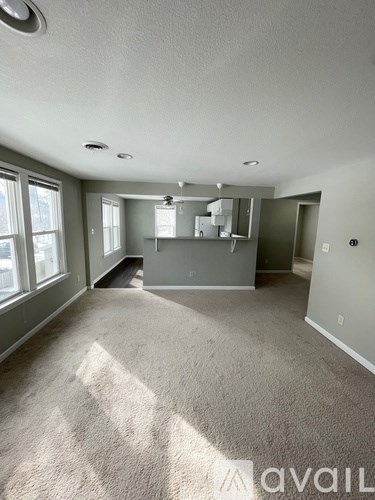 A spacious room with a carpeted floor and a ceiling fan.
