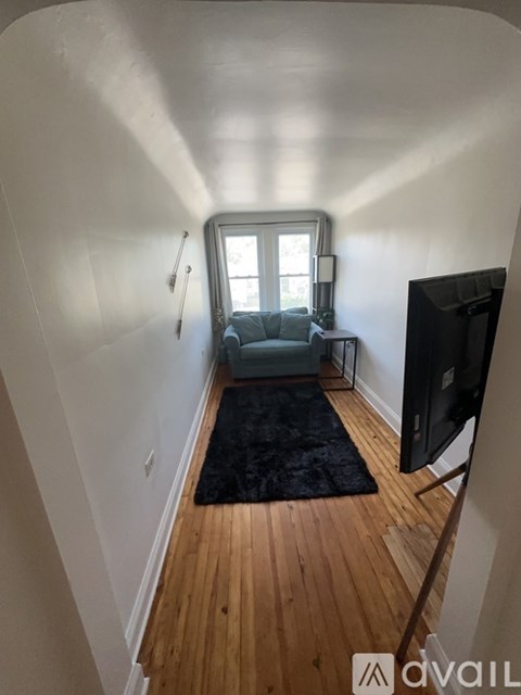 A living room with a grey couch and a black rug.