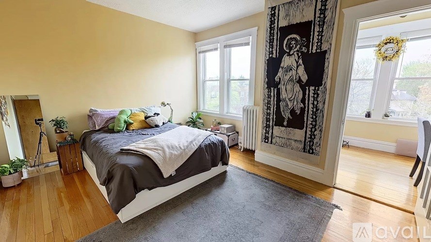 A bedroom with a bed, a chair, a rug, and a framed picture on the wall.
