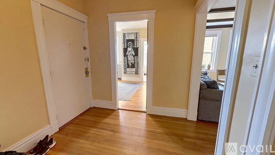 A hallway with a door on the left and a couch on the right.