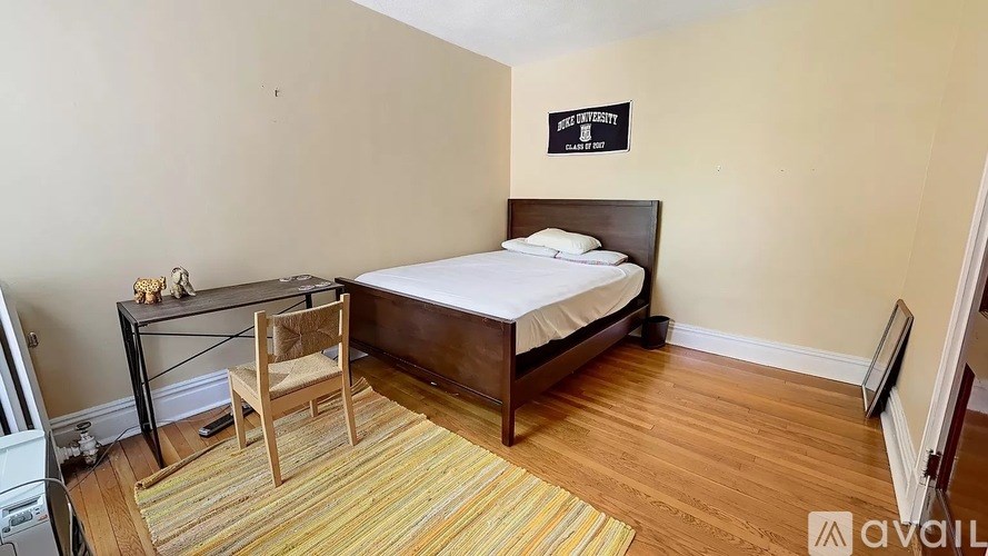 A bedroom with a bed, chair, and a rug.