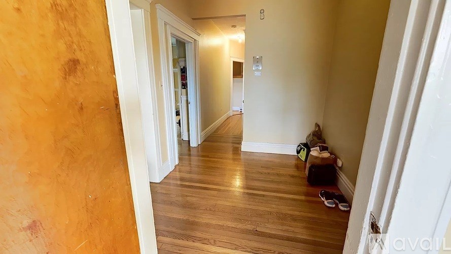 A hallway with a wooden floor and white walls.