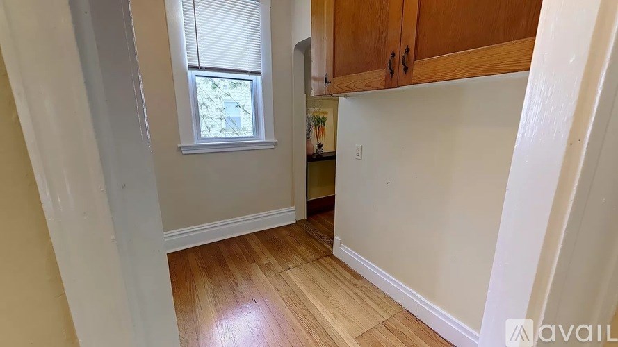 A room with wooden floors and white walls, with a window and a cabinet.