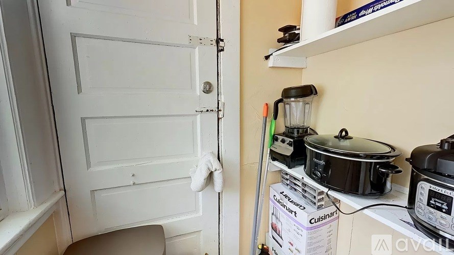 A white door with a white handle and a white wall with a shelf above it.