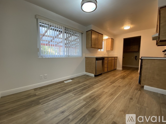A room with wooden flooring and a window with blinds.