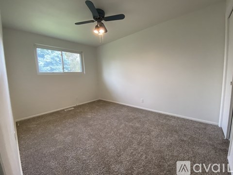 A room with a ceiling fan and carpeted floor.