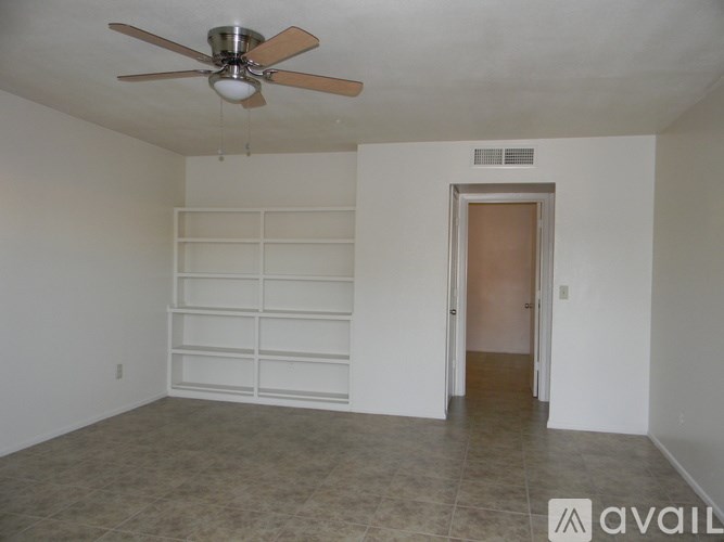 A room with a ceiling fan and a door leading to another room.