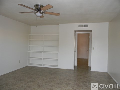 A room with a ceiling fan and a door leading to another room.
