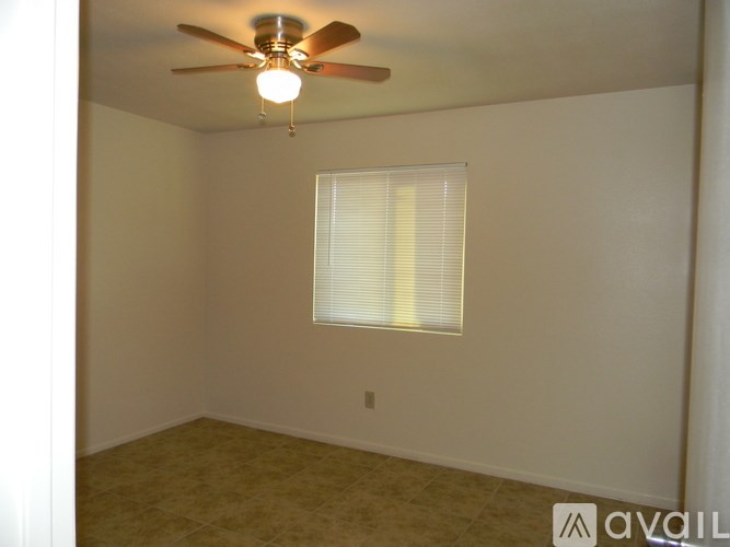 A room with a ceiling fan and a window with blinds.
