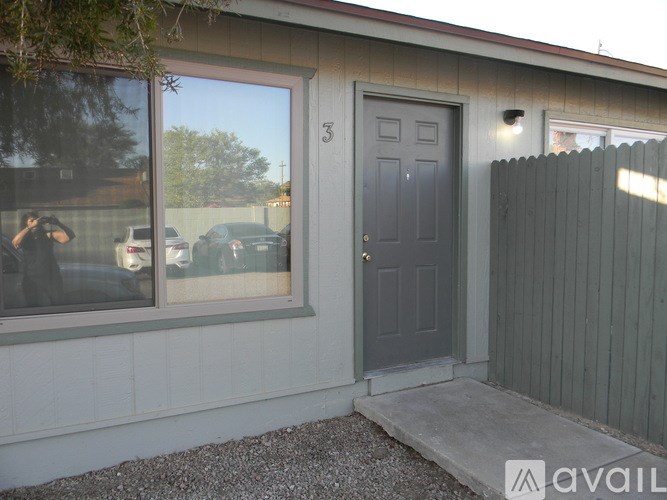 A house with a grey door and a window showing a reflection of cars.