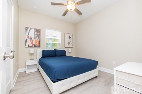 A bedroom with a blue bedspread and white furniture.