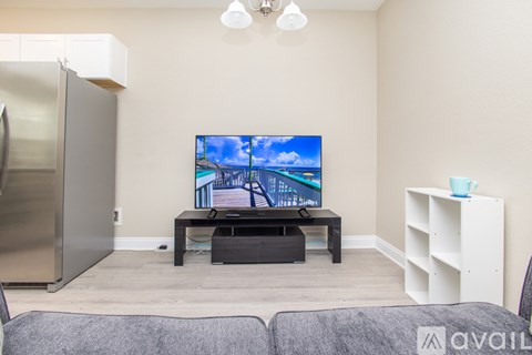 A living room with a television and a grey couch.