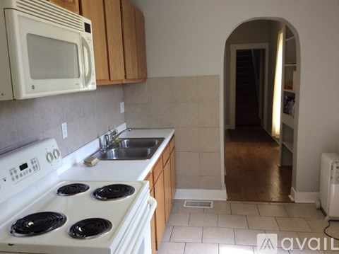 A kitchen with a white stove top oven, a white microwave, and a white sink.