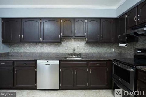 A kitchen with dark brown cabinets and a stainless steel dishwasher.