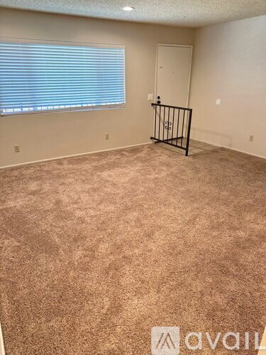 A room with a carpeted floor and a window with blinds.